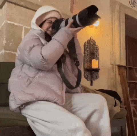 a woman in a pink jacket is taking a picture with her camera