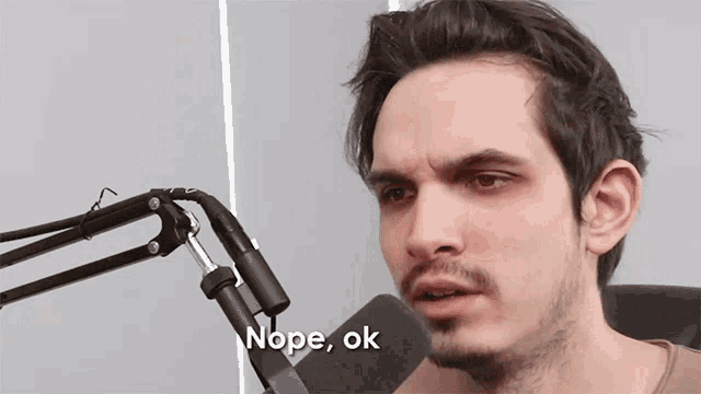 a man sitting in front of a microphone with the words nope ok above him