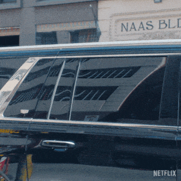 a black car is parked in front of a building that has the word naas on it