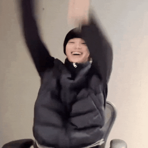 a person is sitting in a chair with their arms up in the air .
