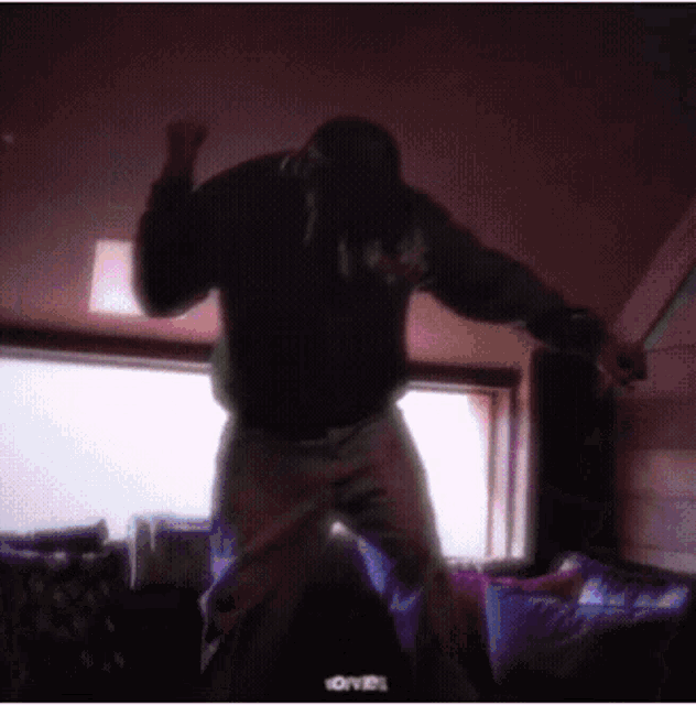 a man in a black hoodie is dancing in a room