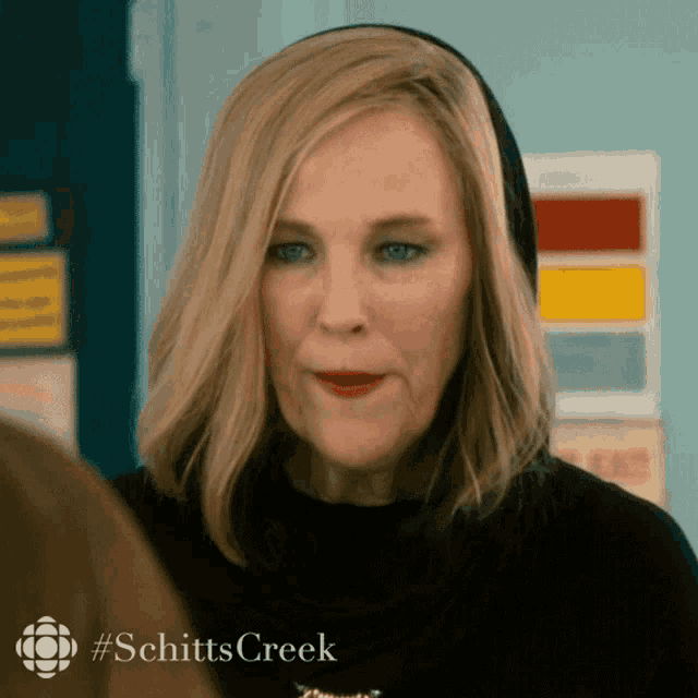 a close up of a woman 's face with the words schitts creek on the bottom right