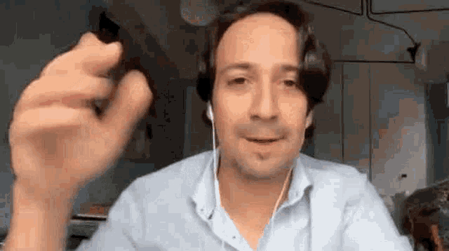a man wearing headphones is talking on a video call while holding a pen .