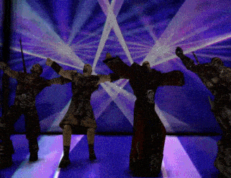 a group of men are dancing in front of a purple light