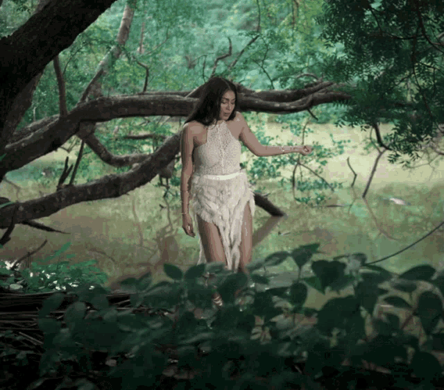 a woman in a white dress is standing in a pond