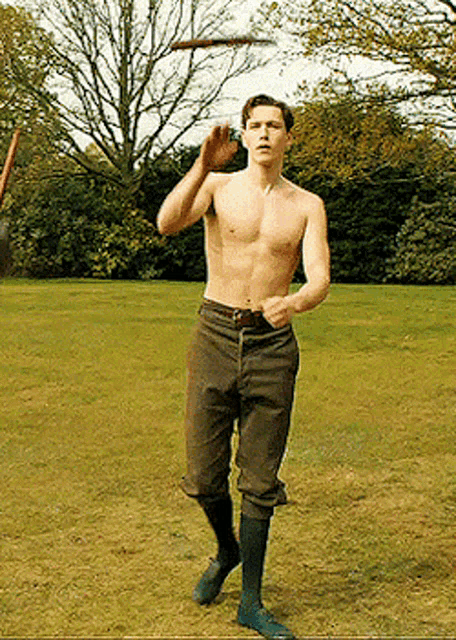 a shirtless man is throwing a frisbee in the air