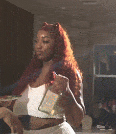 a woman with long red hair is holding a bottle of alcohol