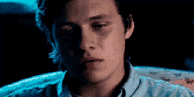a close up of a young man 's face with a blue shirt on .