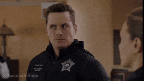 a man in a police uniform is talking to another man in a room .