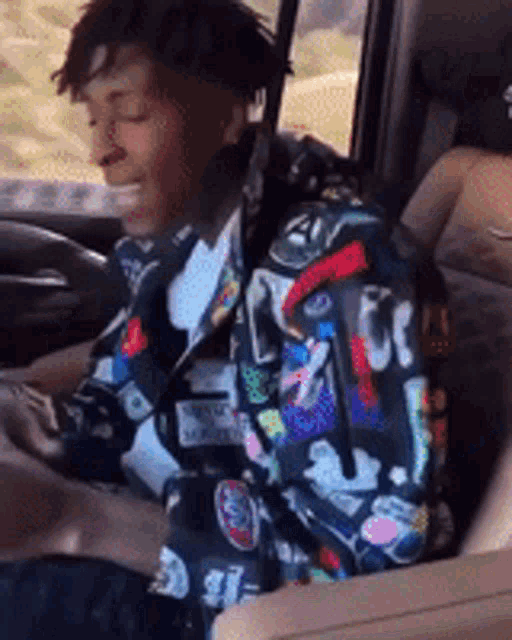 a man is sitting in the back seat of a car looking at his phone