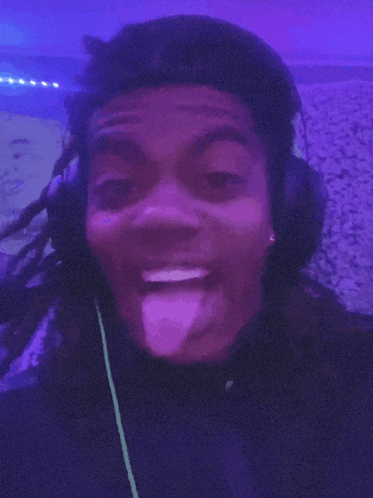 a man wearing headphones sticks out his tongue