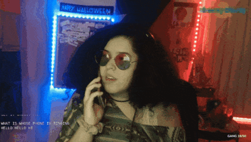 a woman talking on a cell phone in front of a wall that says happy halloween