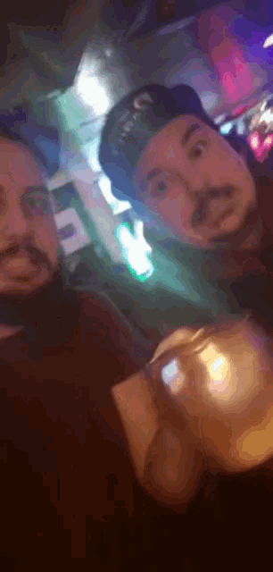 two men are posing for a picture in a dark room with a green light in the background
