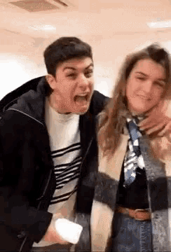 a man and a woman are making funny faces while standing next to each other in a room .