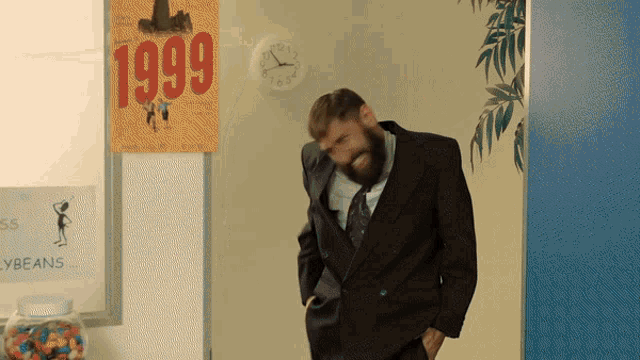 a man in a suit and tie stands in front of a sign that says 1999