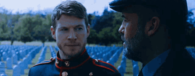 two men are standing in front of a cemetery and talking