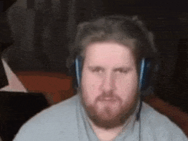 a man with a beard is wearing headphones and making a face .