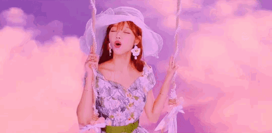 a woman wearing a white hat and earrings is sitting on a swing with her mouth open .
