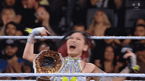 a woman in a wrestling ring is wearing a championship belt