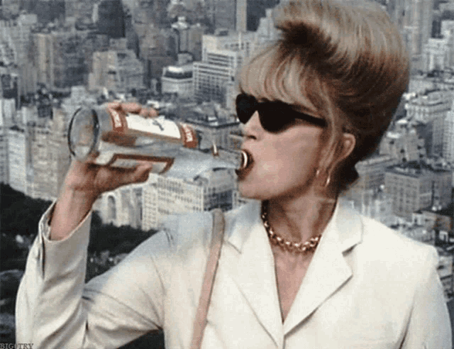 a woman drinking from a bottle with a label that says ' smirnoff '