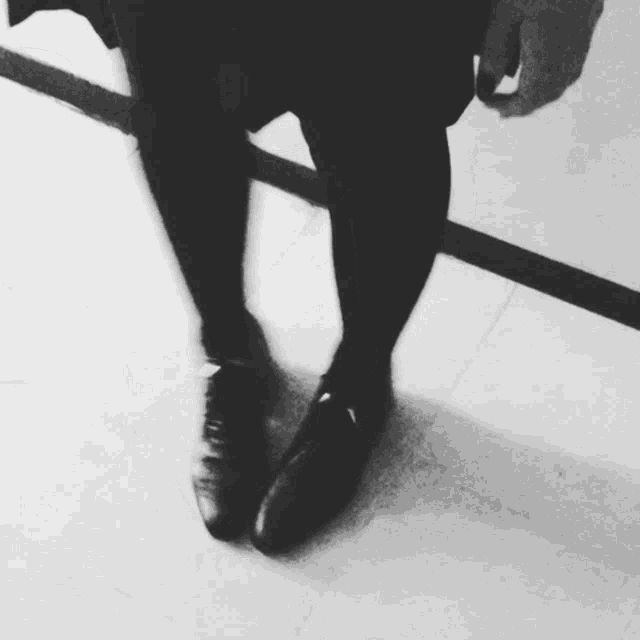 a black and white photo of a person 's legs and shoes