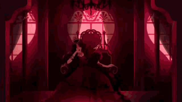 a woman 's hand is holding a red ring in front of a window .