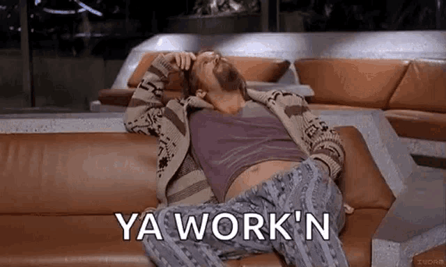 a man with a beard is laying on a couch and saying `` ya work ` ` n '' .