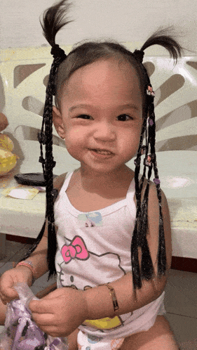 a little girl wearing a hello kitty tank top smiles at the camera