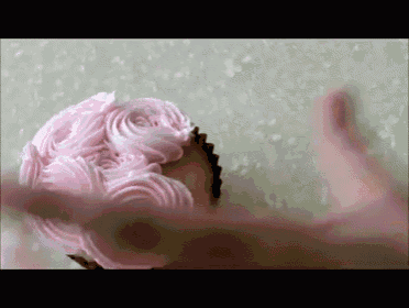 a cupcake with pink frosting that looks like a wig