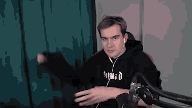 a man wearing headphones and a hoodie is sitting in front of a microphone .