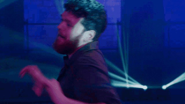a man with a red beard stands in front of a blue background