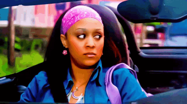 a woman wearing a pink headband and purple purse is sitting in a car