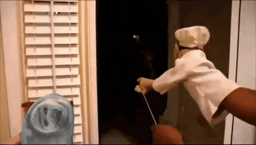 a puppet in a chef 's hat is holding a sword in a dark room