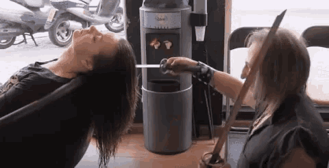 a man is holding a sword over a woman 's head in front of a water dispenser