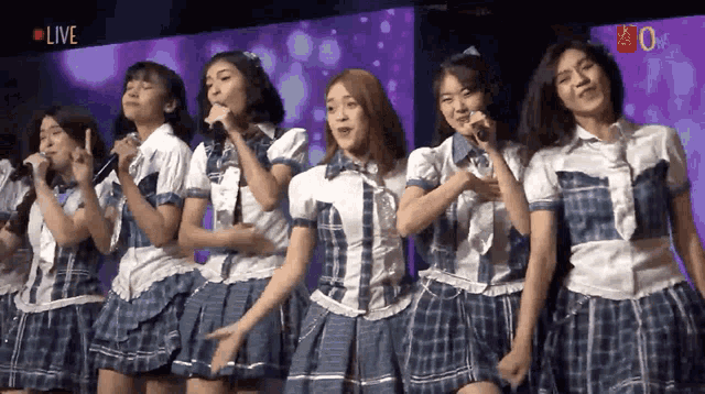 a group of girls are singing into microphones in front of a live screen