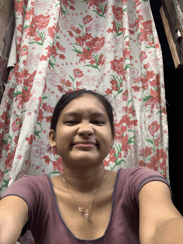 a woman taking a selfie in front of a curtain with flowers on it