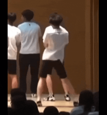 a group of young men are dancing in front of a crowd of people .