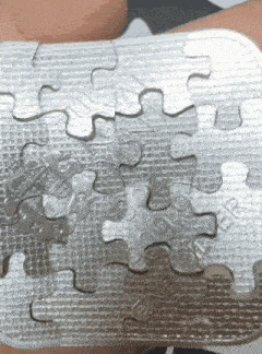 a person is holding a silver puzzle in their hand and the puzzle has the word maker on it