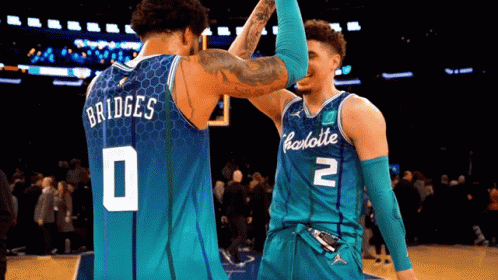 two charlotte hornets players high five each other during a game