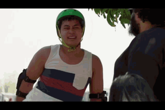 a man wearing a green helmet and a striped tank top