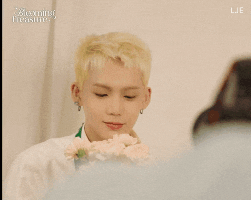 a boy with blonde hair is looking at a flower and the words blooming treasure are on the screen
