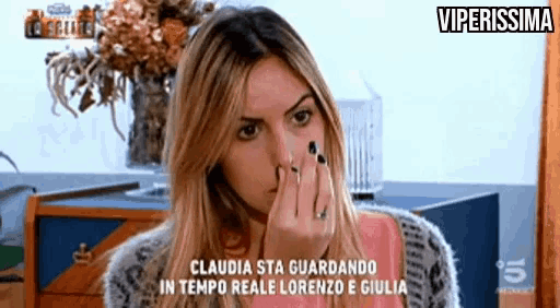 a woman covering her nose with her hand while watching a tv show
