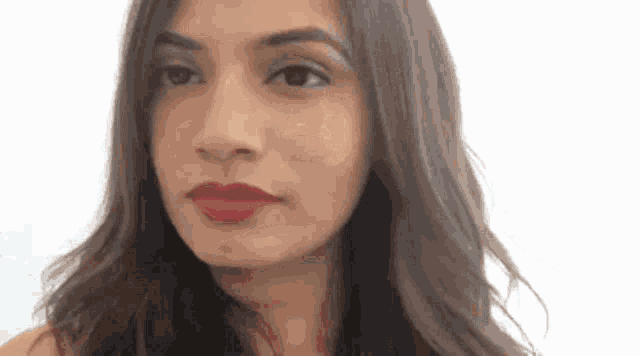 a woman with long hair and red lipstick is looking at the camera .