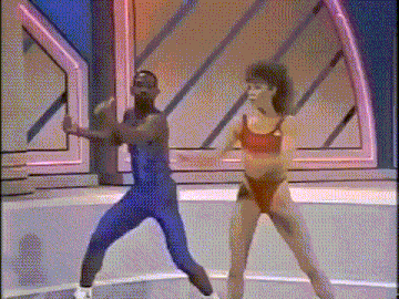 a man and a woman are dancing on a stage in front of a neon light .