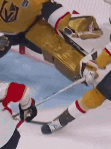 a hockey player is holding a puck in his hand while another player tries to get a puck past him .