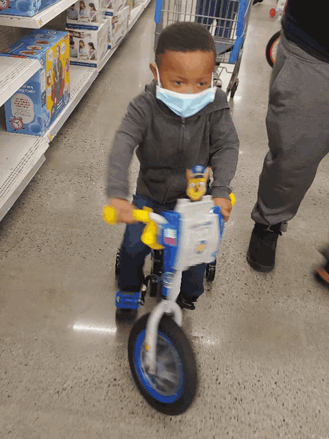 a little boy wearing a face mask is riding a toy bike
