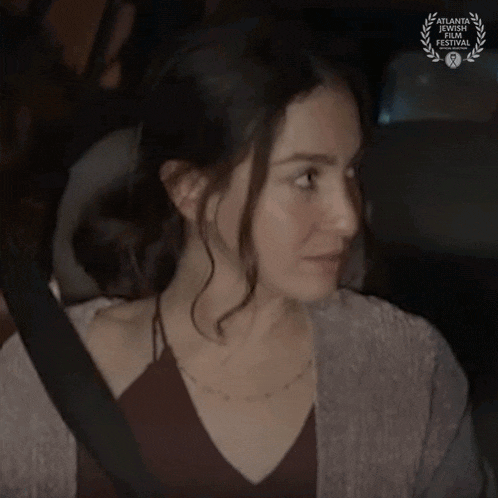a woman is sitting in the back seat of a car and saying okay .