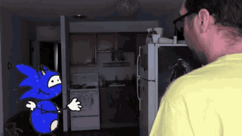 a man in a yellow shirt is looking at a cartoon of sonic the hedgehog in a kitchen