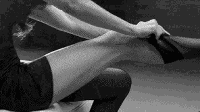 a black and white photo of a woman stretching her legs