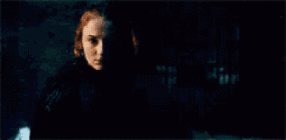 a woman in a dark room with a candle in the background .